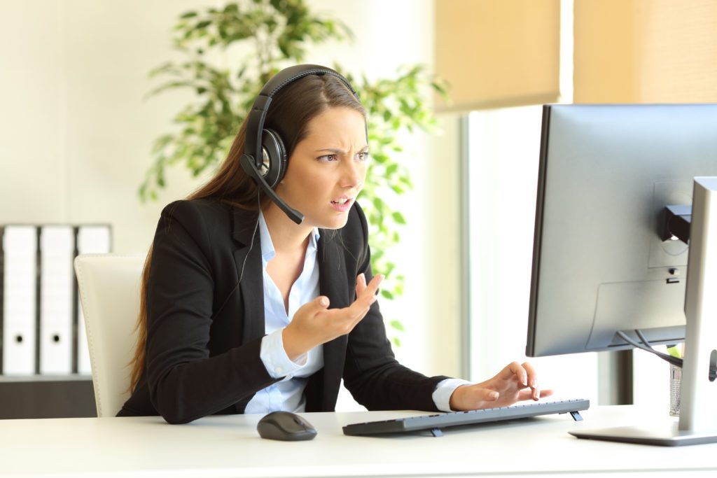 Angry tele marketer attending customer online at office