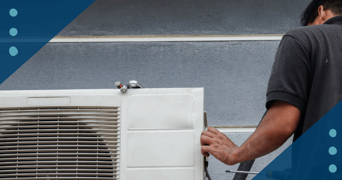 AC technician repairing an AC unit with a screwdriver